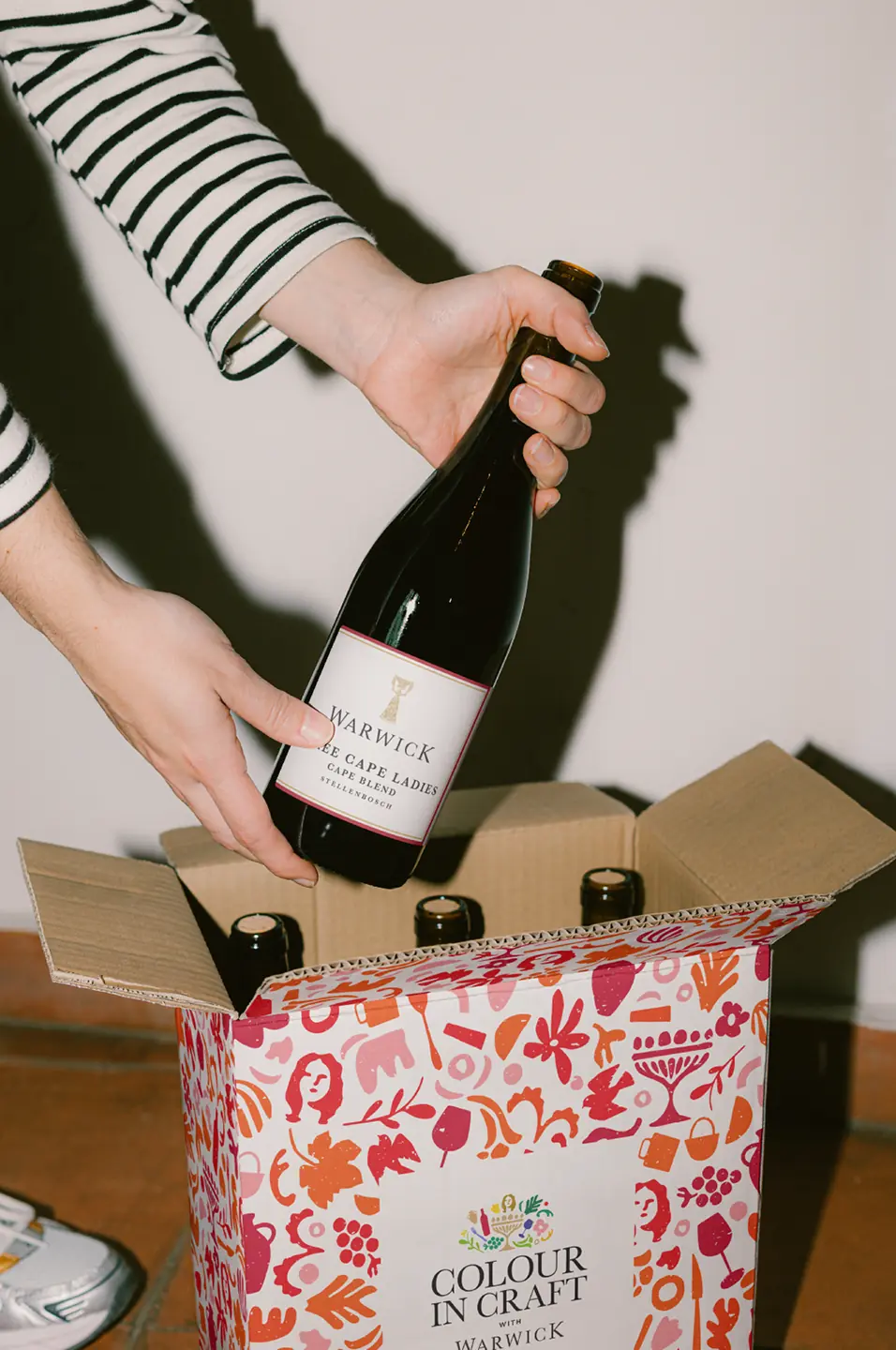 Warwick wine bottle being lifted from a red patterned Colour in Craft gift box